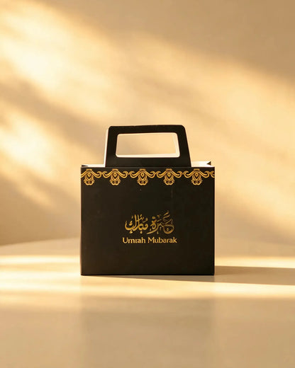Black Umrah Mubarak tote-style gift bag with gold foil border and cutout handle