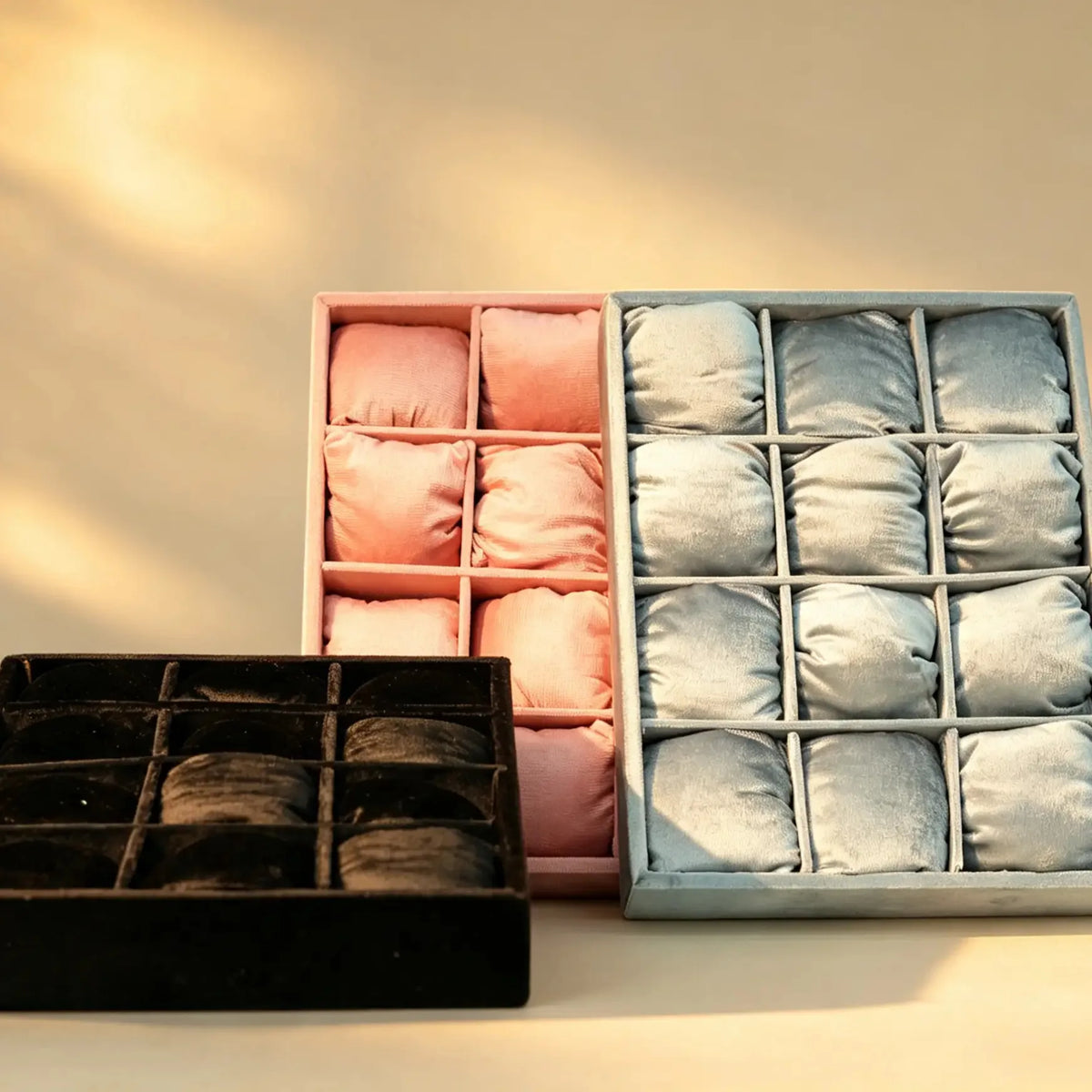 Pink and silver velvet bangle trays with cushioned compartments, plus a black tray in front