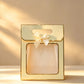 Pale yellow gift bag with gold foil trim, clear front window, and a cream ribbon bow on the handle