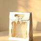 White pearlescent gift bag with silver foil trim, clear front window, and a cream ribbon bow