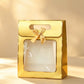 Gold gift bag with matching foil trim, clear front window, and a gold ribbon bow
